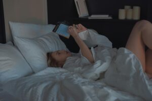A woman comfortably reading a book in a cozy bedroom setting.