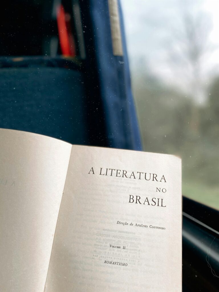 An open book titled 'A Literatura no Brasil' by a window, offering a serene travel experience.